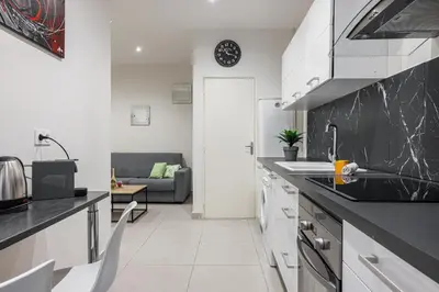 a kitchen with white cabinets and a black counter top at Charming 1 Bdr Old town in Nice