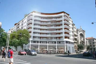 a large white building on a city street with cars at Promenade Gambetta in Nice