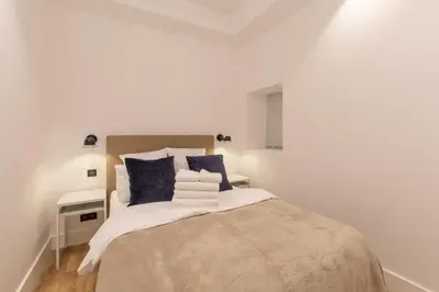 a white bedroom with a large bed with blue pillows at COURS SALEYA Renovated 3 Bedrooms 1 min to Beach Air Conditioning in Nice