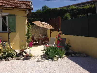 a patio with a table and an umbrella in a backyard at Le 43 in La Trinité