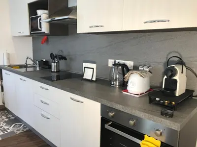 a kitchen with white cabinets and a black counter top at Chouette Massena in Nice