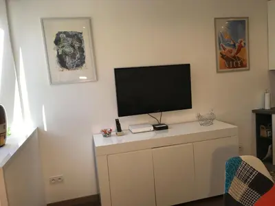 a living room with a television on a white cabinet at Chouette Massena in Nice