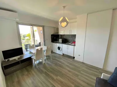 a living room with a dining table and a kitchen at Studio, piscine in Saint-Laurent-du-Var