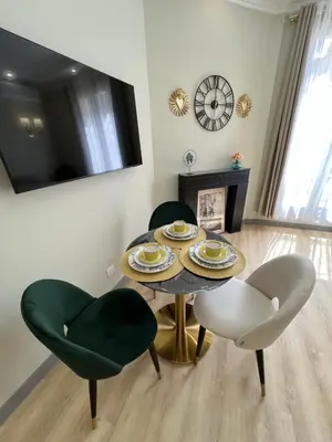 a dining room with a table and chairs and a clock at Amour-35 in Nice