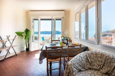 a living room with a table with a view of the water at BELVEDERE AP1059 Villefranche-sur-Mer by Riviera Holiday Homes in Villefranche-sur-Mer