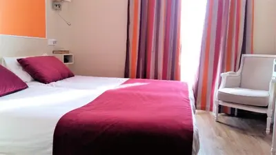 a bedroom with a bed and a chair and a window at Hotel Le Havre Bleu in Beaulieu-sur-Mer