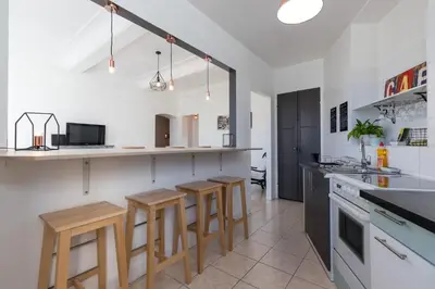 a kitchen with white walls and wooden stools at Bright Apartment Old Town in Nice