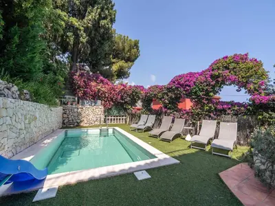 a swimming pool with chairs and a wall with flowers at Elegant Seaside Villa in Èze in Èze