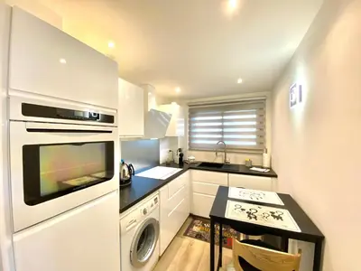 a kitchen with white cabinets and a sink and a stove at Eden Barmassa in Villefranche-sur-Mer