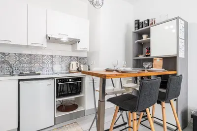 a kitchen with white cabinets and a wooden table with chairs at COCOON BEACH Central Proche Mer in Nice