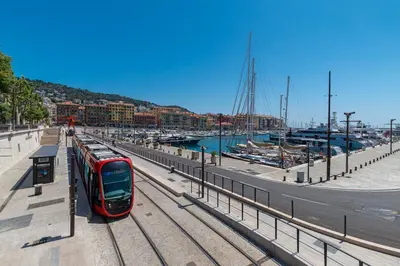 a red train on tracks next to a harbor at COCOON BEACH Central Proche Mer in Nice
