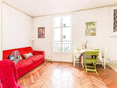 a living room with a red couch and a table at Apartment France by Interhome in Nice
