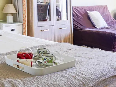 a tray with two cups and a bowl of strawberries on a bed at Apartment La Floride Promenade des Anglais by Interhome in Nice