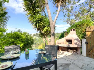 a table and chairs with a pizza oven in a yard at Holiday Home Agora by Interhome in Nice