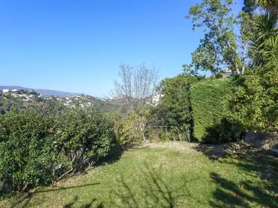 a yard with bushes and trees on a hill at Holiday Home Agora by Interhome in Nice