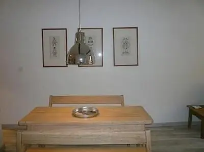a wooden table in a room with three pictures on the wall at Appartement Les Plages in Nice
