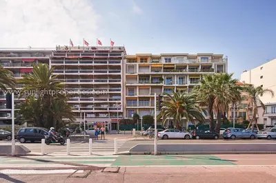a large building with palm trees in front of it at Sunlight Properties - 