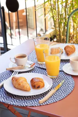 a table with plates of pastries and cups of orange juice at L'Abeille - Boutique Apartments in Nice