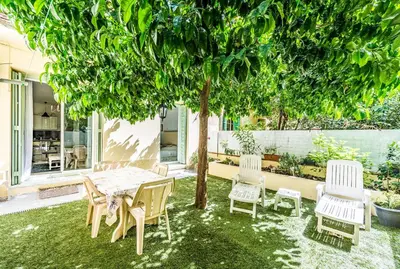 a table and chairs under a tree in a yard at la palais osiris Nice centre jardin wifi clim parking in Nice