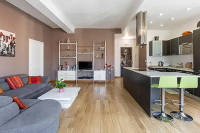 a living room with a gray couch and a kitchen at Le Blacas in Nice