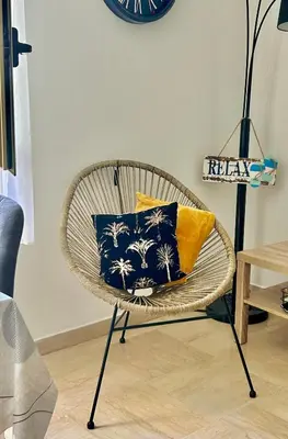 a wicker chair with pillows on it in a room at Charmant Studio en bord de Mer in Nice