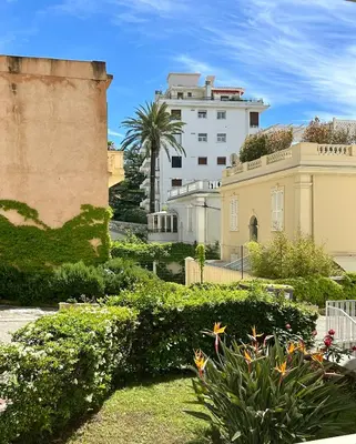 a large building with a palm tree in the background at Charmant Studio en bord de Mer in Nice