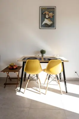 a dining table with two yellow chairs and a table at Chic appartement Centre NICE au calme vue colline in Nice