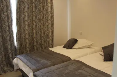 a bedroom with two beds and a window with curtains at Les Bastides D'Hélène in Èze