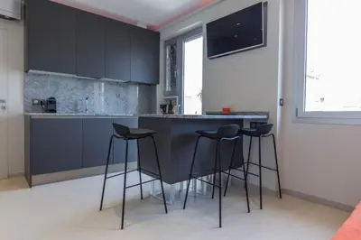 a kitchen with black cabinets and bar stools at Nice Jean Médecin in Nice