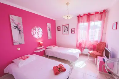 a pink room with two beds and a chair at LA CASETTA DEI FIORI VI3078 in Nice
