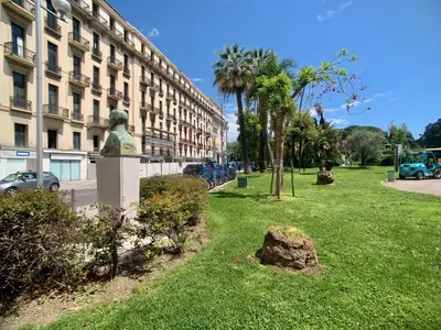 a statue in a park in front of a building at Palais Massena - Easy Home Booking in Nice