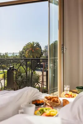a table with two plates of food on a bed with a window at Albert 1er in Nice