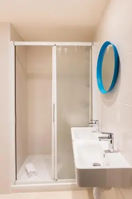 a bathroom with a shower and a sink and a mirror at Hostel Ozz Nice in Nice