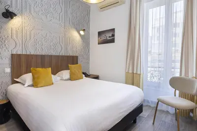 a bedroom with a large bed with yellow pillows at Best Western Plus Hôtel Brice Garden Nice in Nice