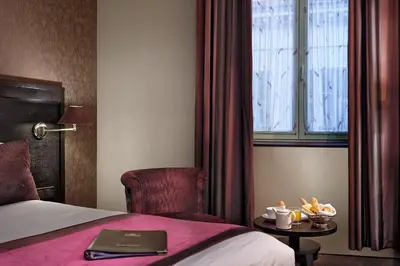 a hotel room with a bed and a chair and a window at Best Western Plus Nice Cosy Hotel in Nice