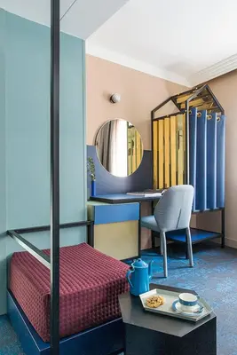 a bedroom with a bed and a desk and a mirror at Hôtel les Cigales in Nice