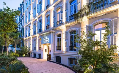 a large white building with blue windows at Hôtel Apollinaire Nice in Nice