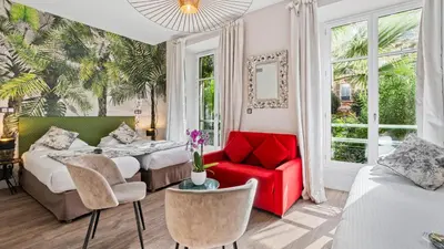 a bedroom with two beds and a red chair at Hotel Villa Victoria in Nice