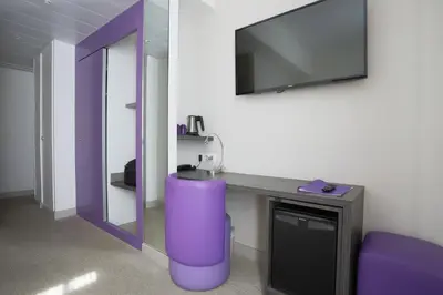 a room with a purple stool and a mirror at Hôtel de la Fontaine in Nice