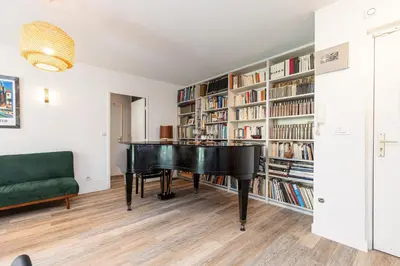 a black piano in a room with bookshelves at 2 Bdrs & Parking in the Old Town ! in Nice