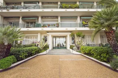 an exterior view of a building with palm trees at LES MOUETTES - PROMENADE HOLIDAY in Nice