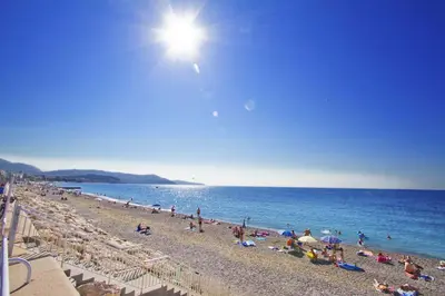 a group of people on a beach with the sun at LES MOUETTES - PROMENADE HOLIDAY in Nice