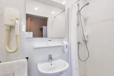 a white bathroom with a shower and a sink at Hotel Lepante in Nice
