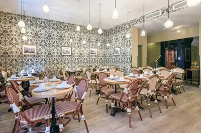a dining room with tables and chairs and a patterned wall at Hotel Le Grimaldi by Happyculture in Nice
