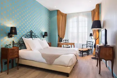 a hotel room with a bed and a television at Hotel Le Grimaldi by Happyculture in Nice