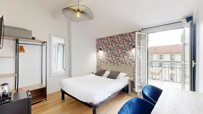 a bedroom with a bed and a large window at Hotel Solara in Nice