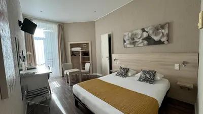 a hotel room with a bed and a desk in it at Hôtel Helvétique in Nice