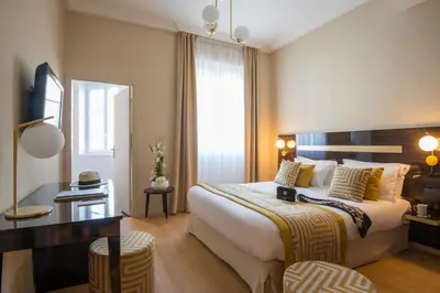 a hotel room with a large bed and a desk at Hotel Carlton in Beaulieu-sur-Mer