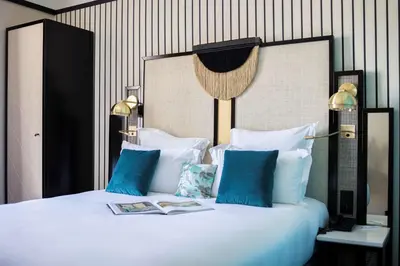 a large white bed with blue pillows in a room at Best Western Premier Hotel Roosevelt in Nice