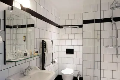 a white tiled bathroom with a sink and a toilet at Best Western Premier Hotel Roosevelt in Nice